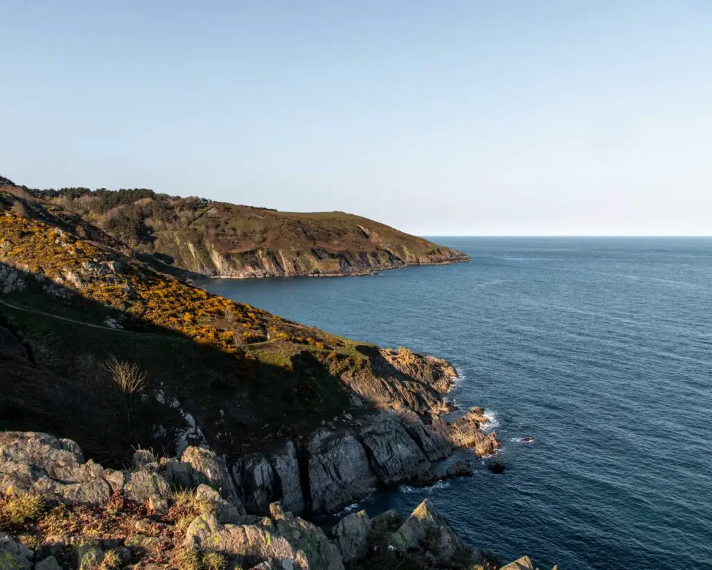 The rocky, cliff coastline as it meets the blue sea on the hike near Dartmouth.