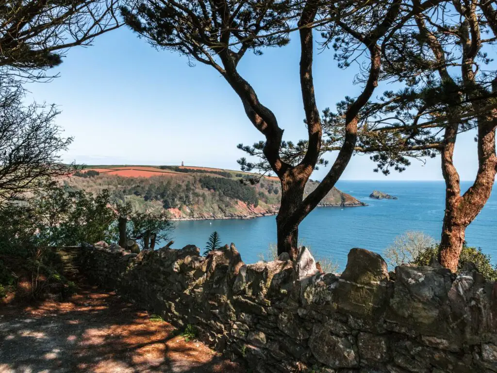 A view through some trees to the blue sea and peninsula on the Little Dartmouth walk. The Daymark is just about visible on the peninsula. 