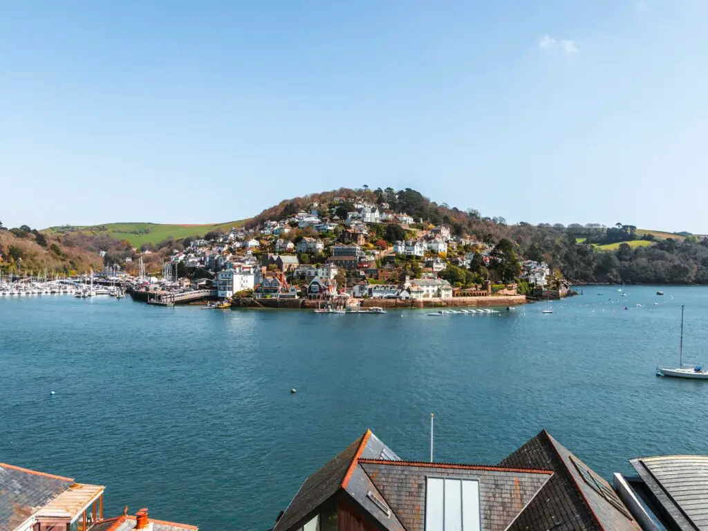 A view across the River Dart to a hill with lots of buildings and homes on the Little Dartmouth walk.