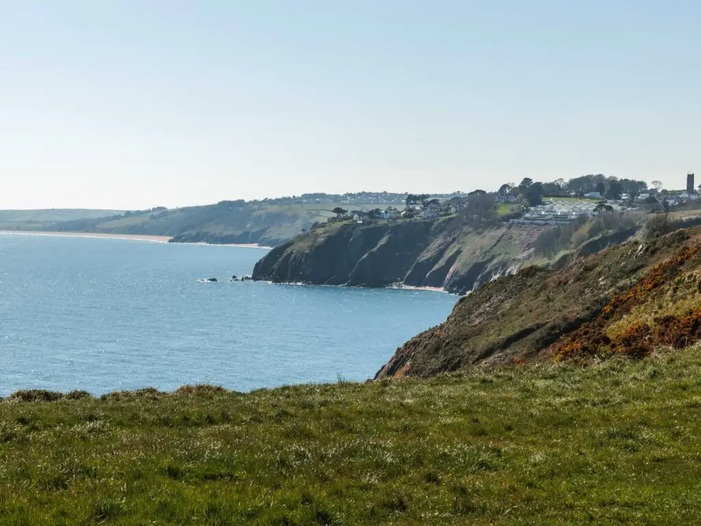 A view across the green to the cliff coastline as it meets the blue sea.