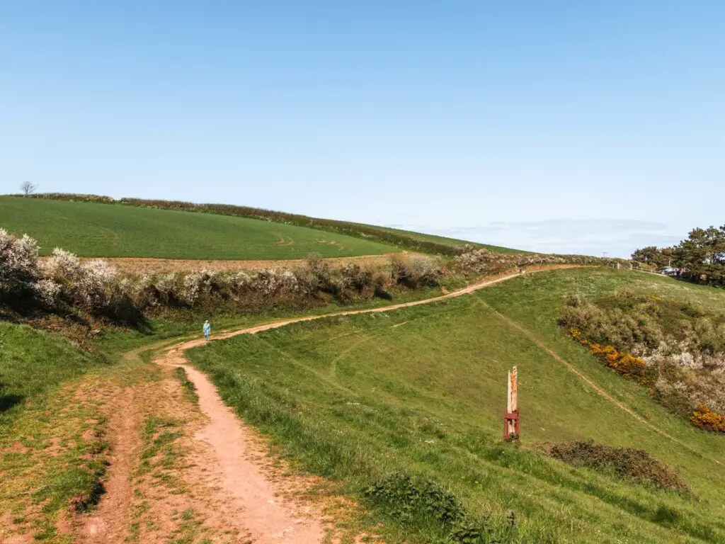 A dirt trail running along the top of a green grass hill.