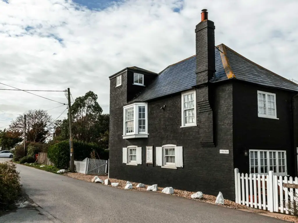 A black bustling with white window frames on the walk into Rye Harbour.
