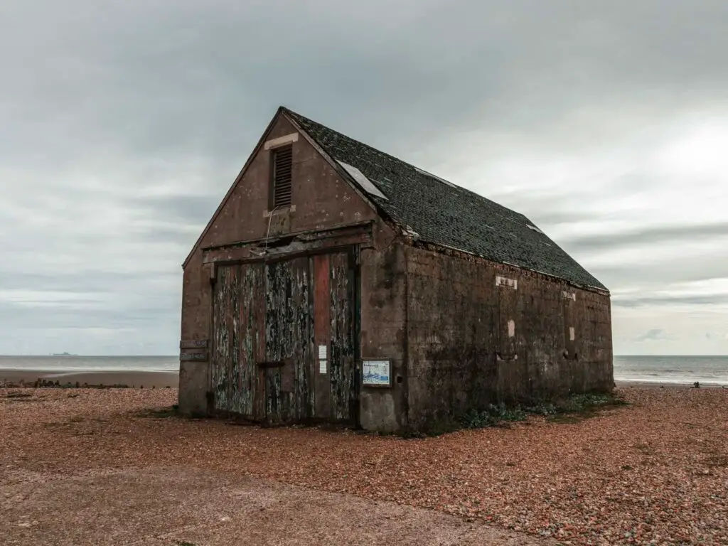 A run down shed sitting on shingle on the walk along the coast path from Rye.
