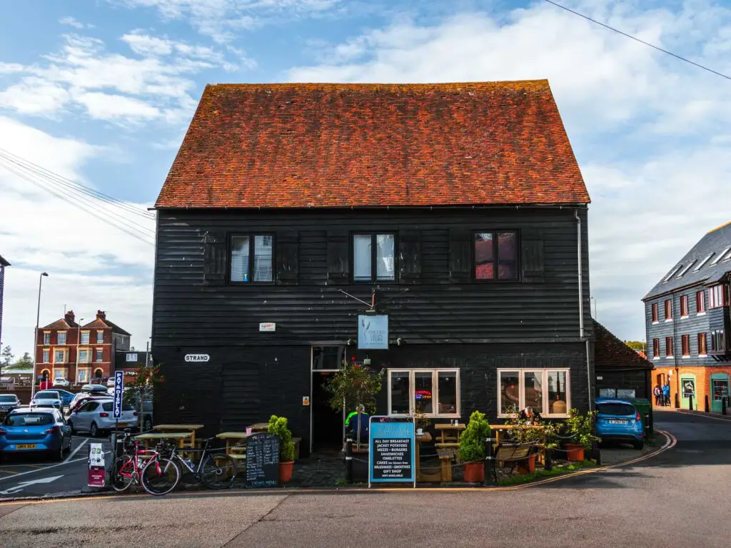A black wood building with a red roof on the walk out of Rye.