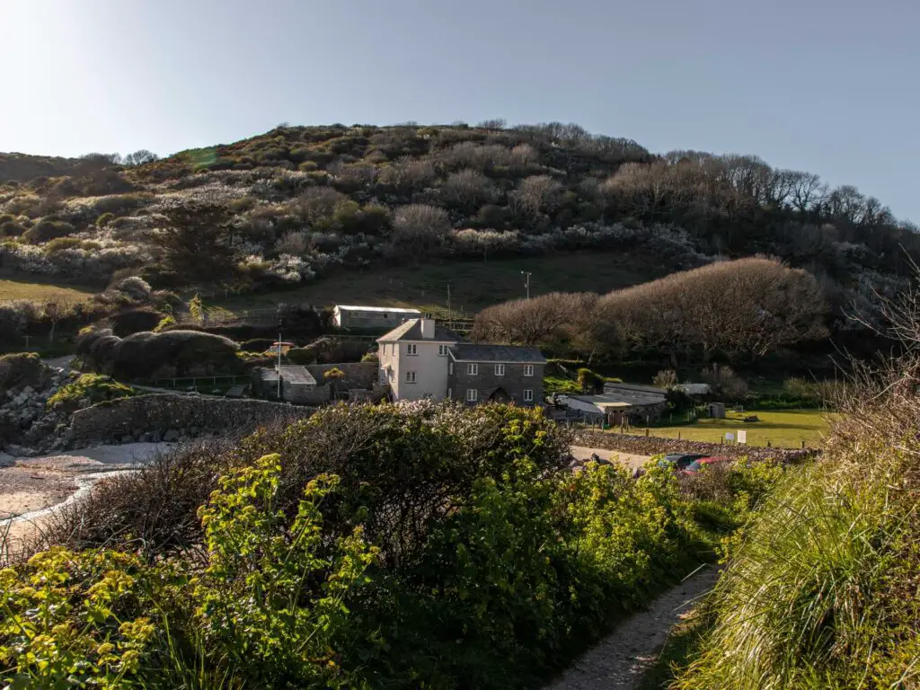 Some buildings at the bottom of a hill, infant of a beach.