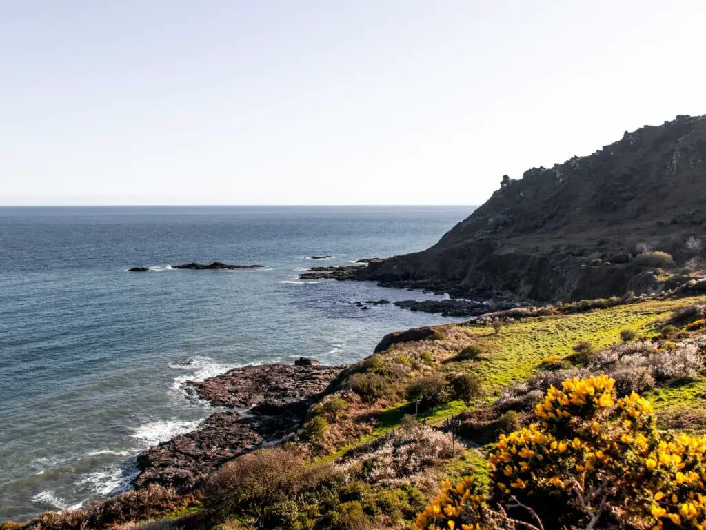 A view of the rocky, cliff coastline as it meets the blue sea in South Devon.