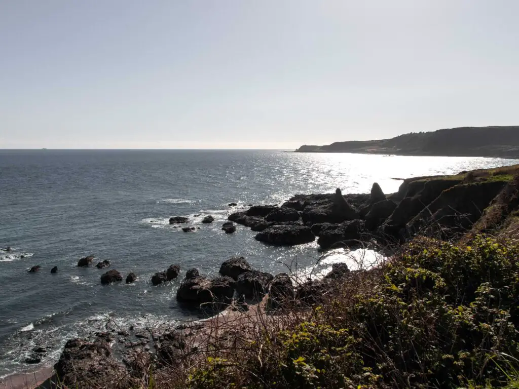 Black rocks jutting out into the blue sea.