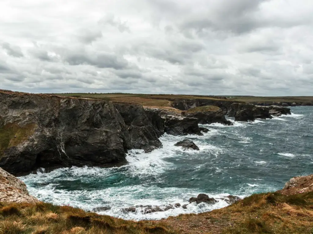 Looking down and across the craggy coastline as the sea crashes into it.