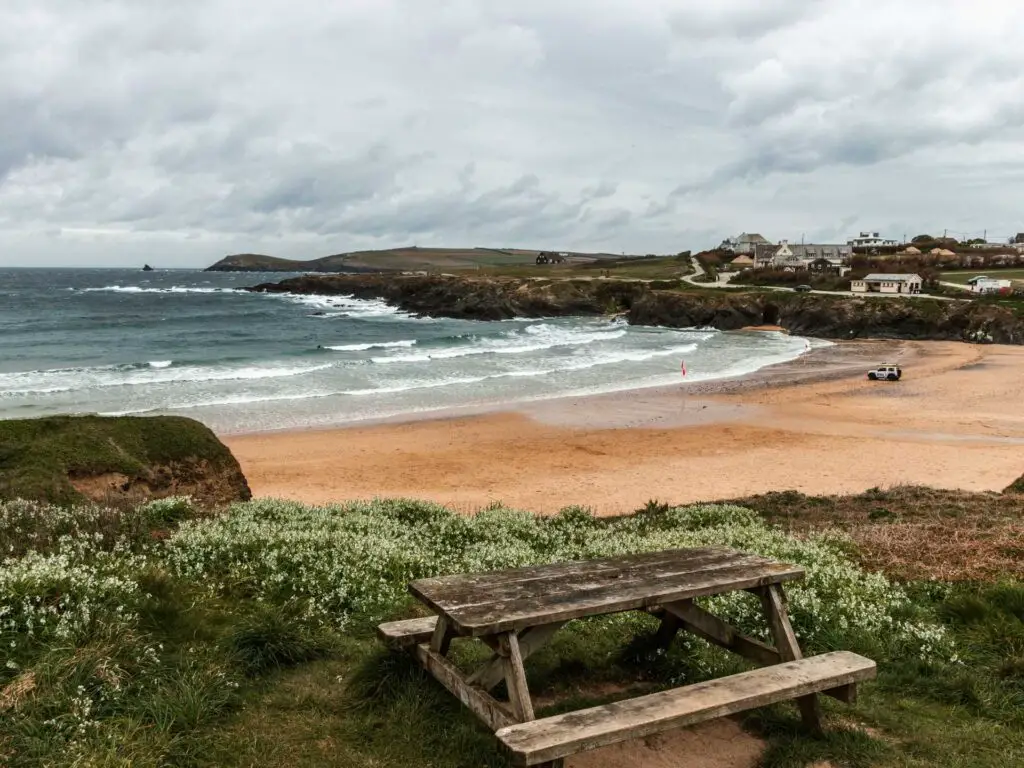 Looking past a wooden picnic bench and down to the sand and sea of Treyanon Beach.