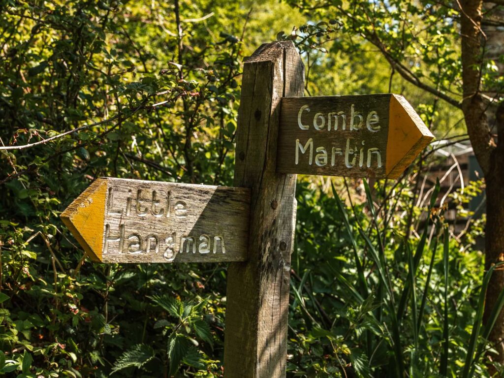 Wooden signpost pointing to little hangman and Combe Martin.