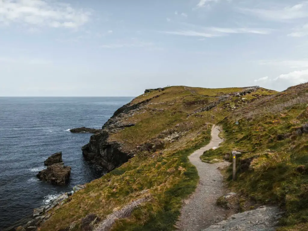 A small trail along the top of the cliff leading to Barres nose in Tintagel. The sea is dark blue where is meets the cliff.