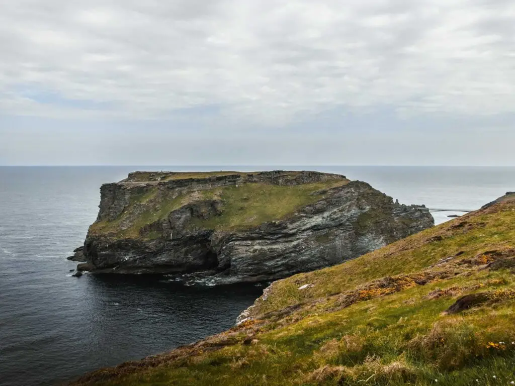 The craggy Tintagel island surrounded by the dark blue sea.