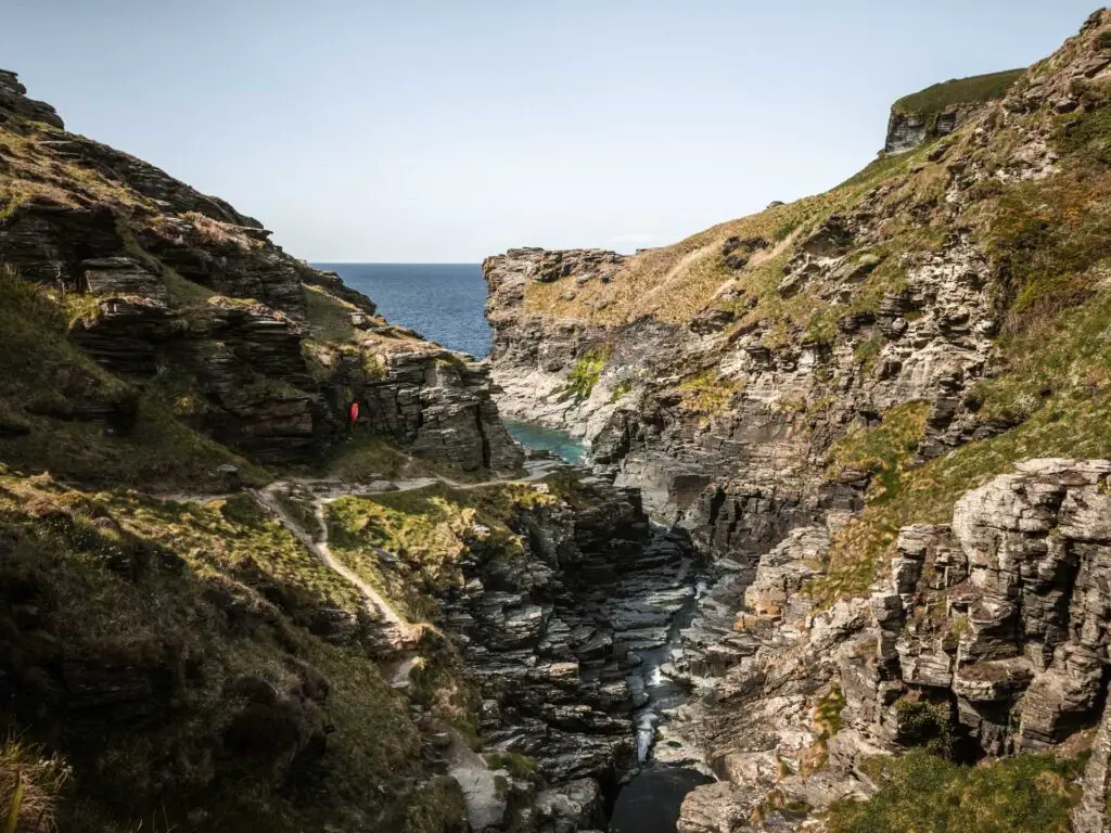 Looking through the craggy cliffs with a river running through it to the blue sea on the other side.