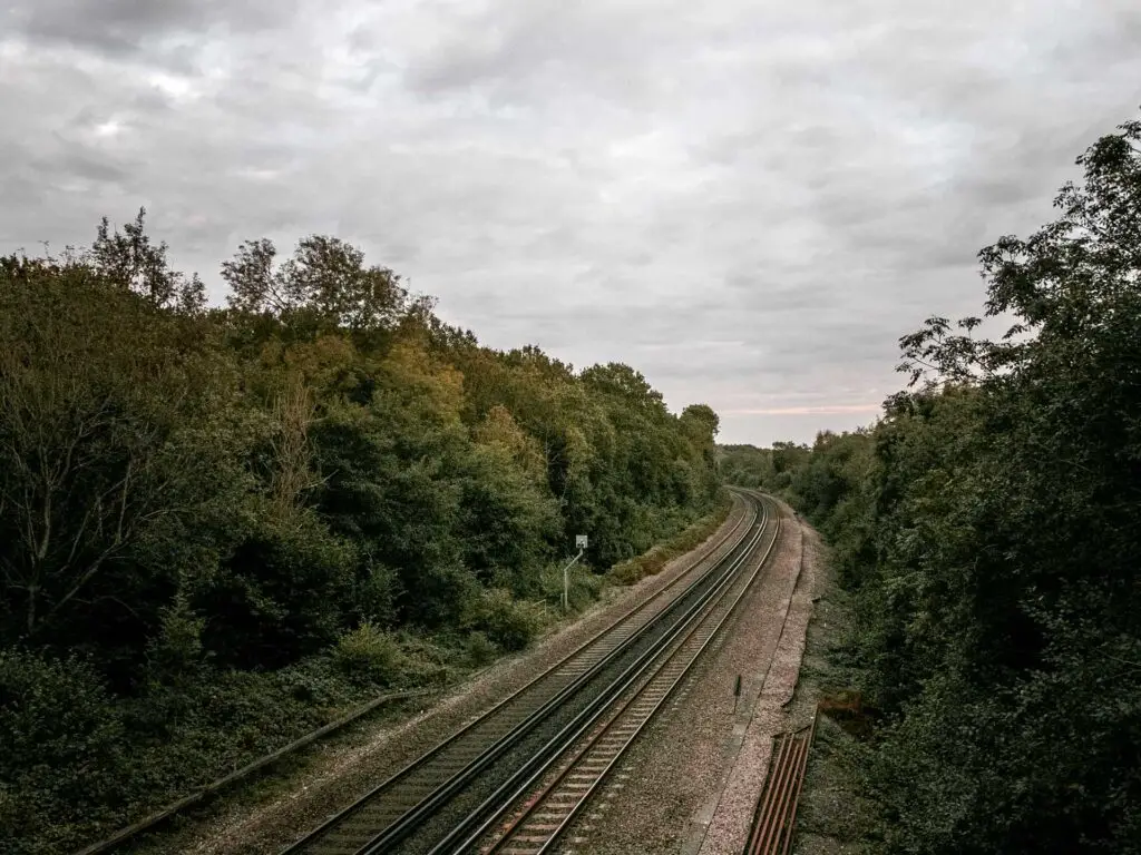 Looking down at the railway tracks at the end of the circular walk from Balcombe to ardingly reservoir and the ouse valley viaduct. the train tracks are lines with dense bushes and trees either side.