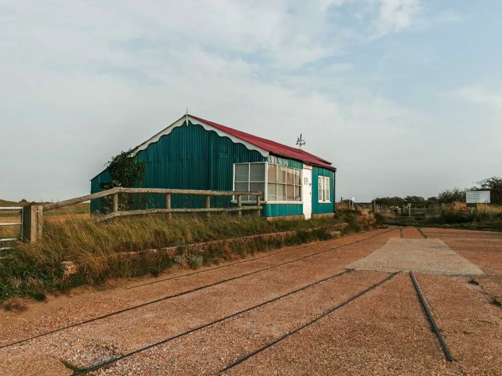 The old Rye and Camber Tramway station with tramway tracks running in front of it. The building is green with a red roof.