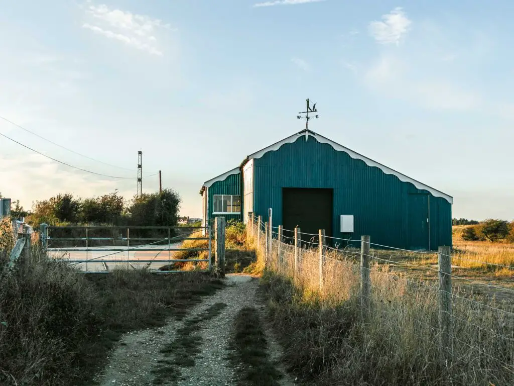 A gravel dirt trail leading to the old tramway station building on the walk back to Rye from Camber Sands.