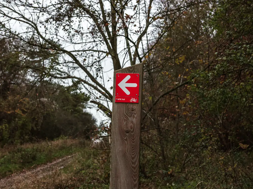 A wooden signpost with a red mountain bike sign.