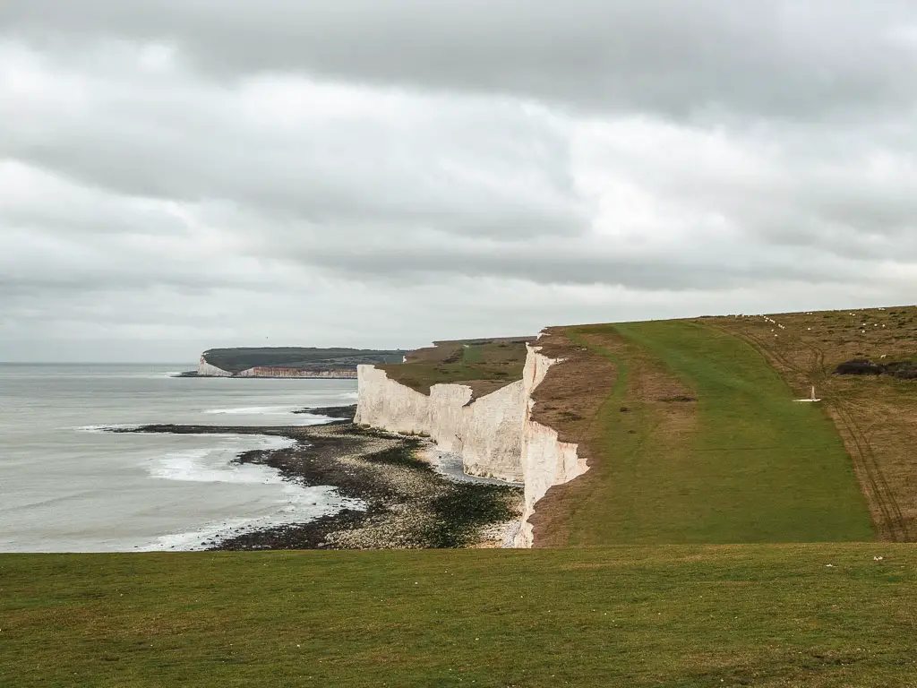 Looking down across the grass covered clifftop of the Seven Sisters cliffs on the circular walk away from Birling Gap.