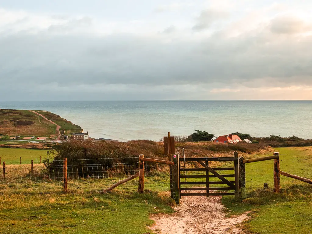 A wooden gate in the field, on the walk back to Birling Gap, witch is just visible. The blue sea is ahead.