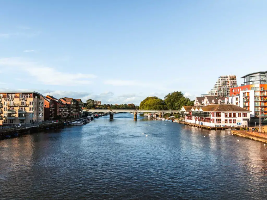 Standing on Kingston bridge looking down the River Thames towards the railway bridge on the walk from Richmond to Hampton Court and bushy park. The river is lined with blocks of flats.