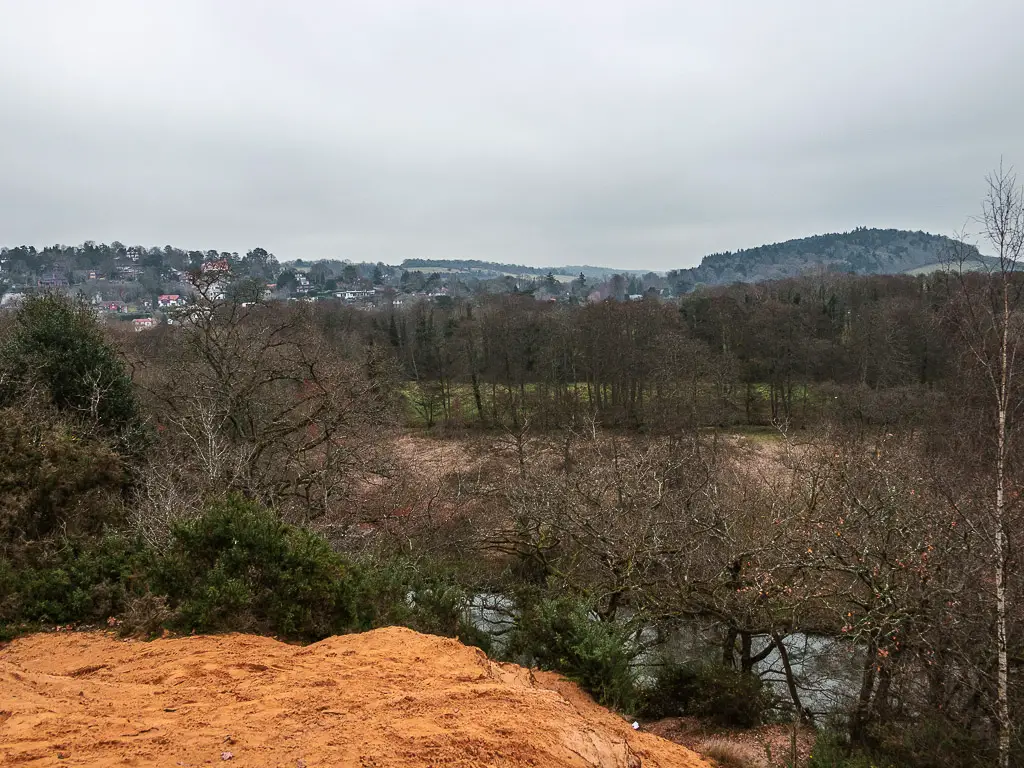 On top of a hill, looking down to the trees, and the Surrey hills in the distance.