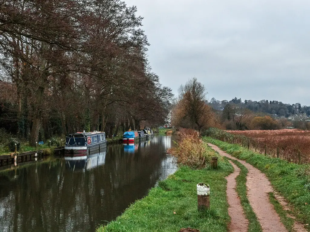 The trail on the right on the walk from Guildford to Godalming, with some barges moored along the River Wey to the left.