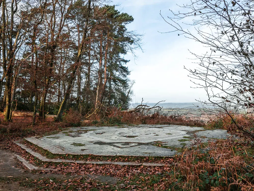 The base of Temple of the four winds on the hindhead devil's punch bowl walk. The base is surrounded by trees, with an opening out to the views.