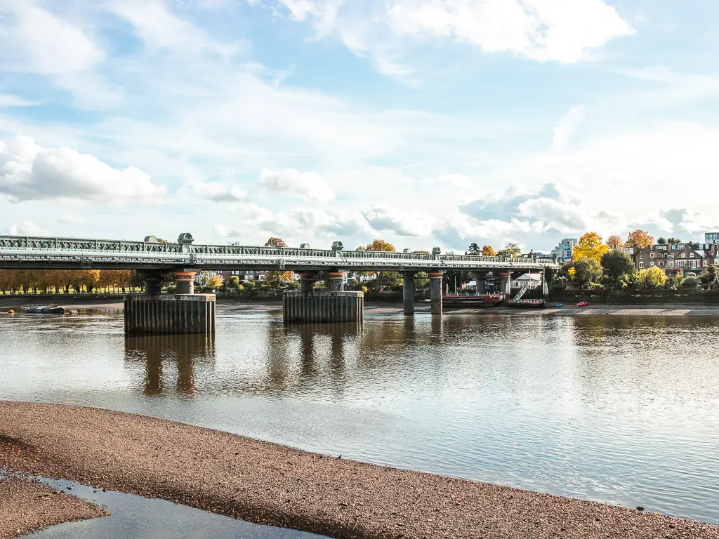 Fulham Railway Bridge across the water of the River Thames. The sky is blue with a few white clouds.