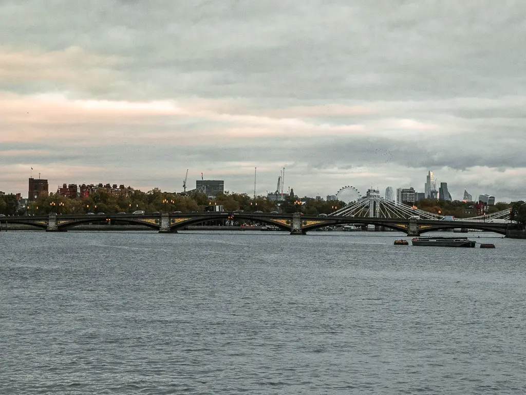 A view down the River Thames towards Battersea Bridge on the walk from Putney along the Thames Path. Past the bridge you can see skyscrapers from the city of London, and the London Eye. 