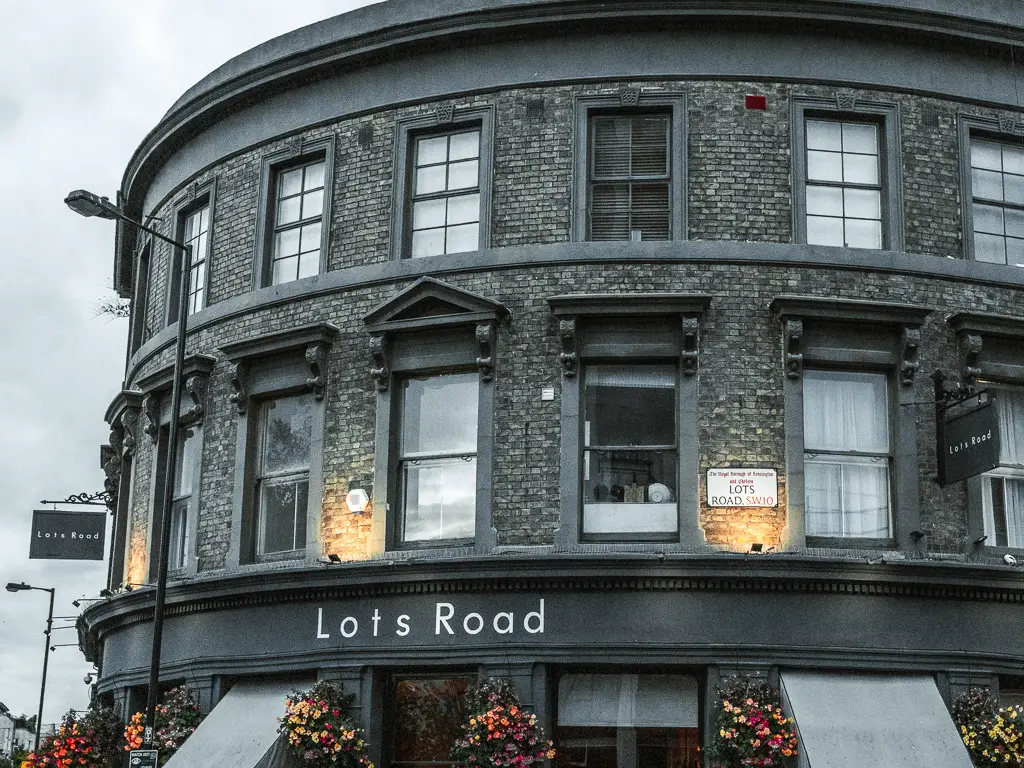 A curved grey buildings with lots of windows above Lots road pub.