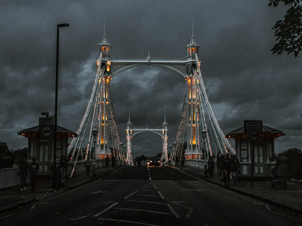 Looking along Albert Bridge at night. the Bridge is lit up by lights.