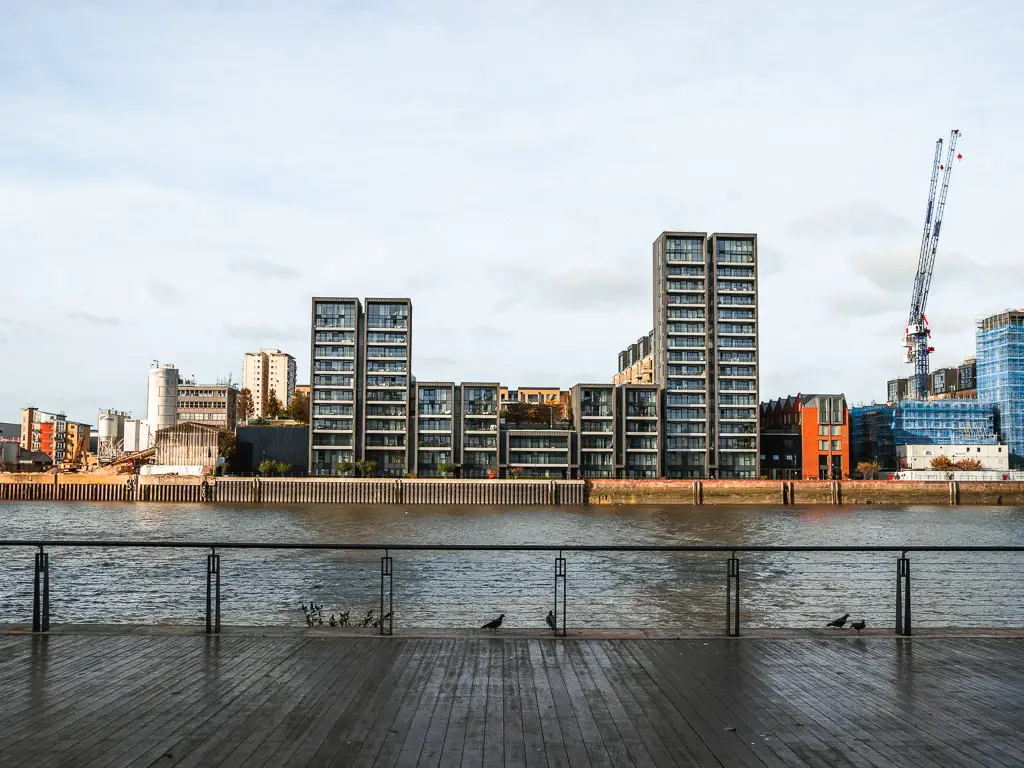 Looking across a platform to the River Thames and apartment buildings on the other side.