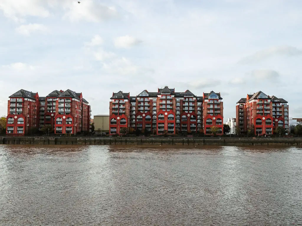 Red coopered apartments buildings on the other side of the river on the Thames Path walk from Putney to Battersea.