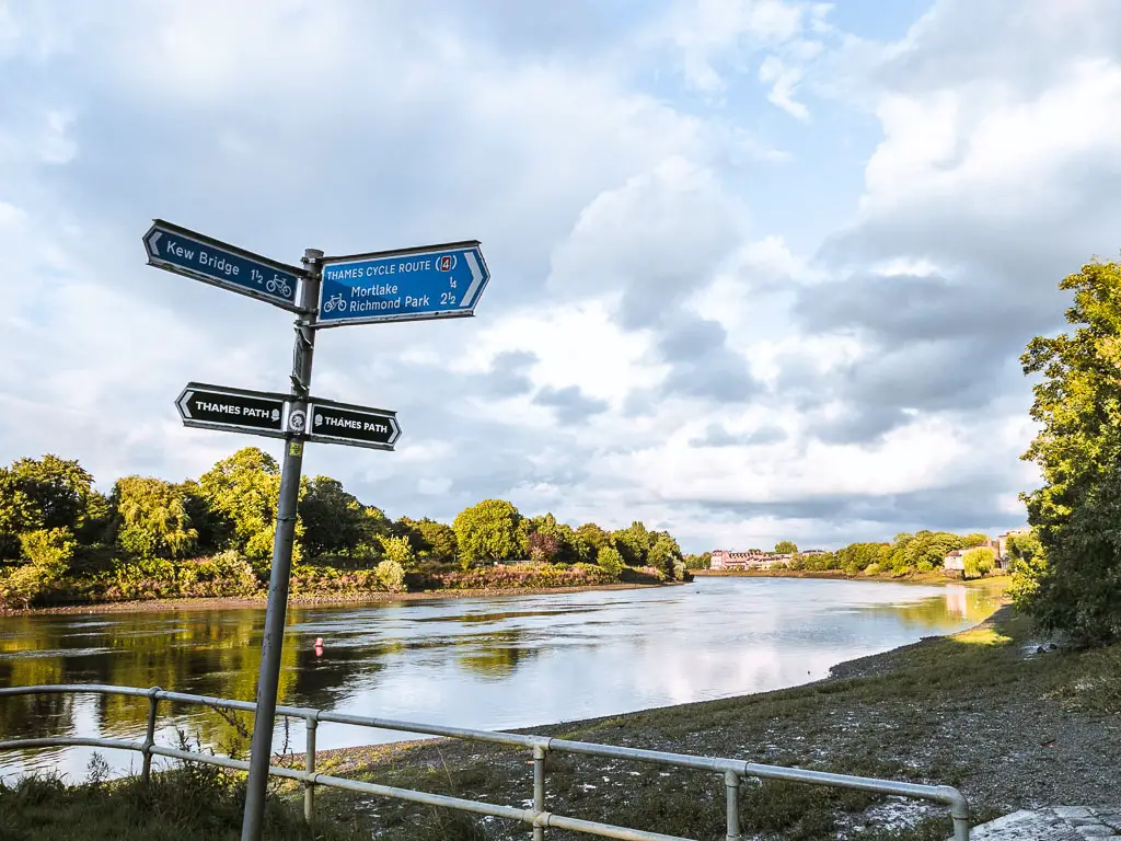 A signpost infant of the river, pointing to the Thames Path.