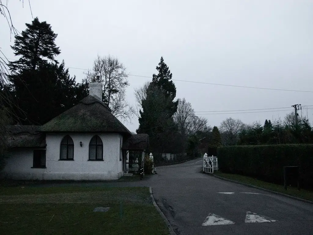A road with a white building on the green on the left.