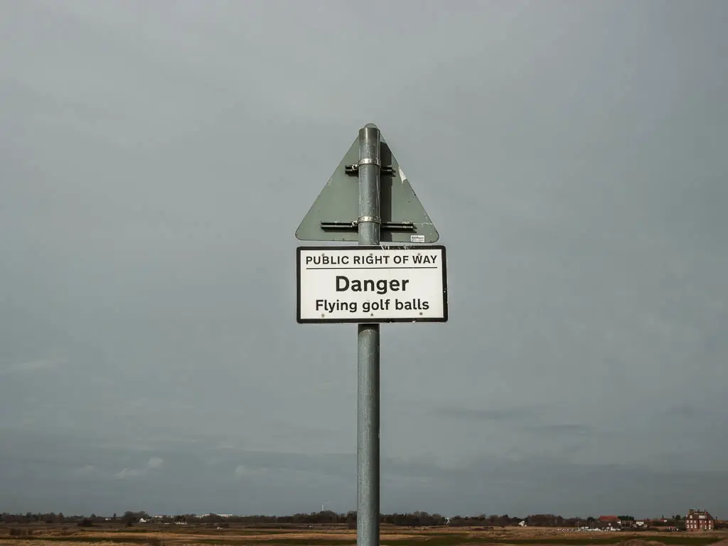 A metal pole with a sign saying 'Danger, flying golf balls'.