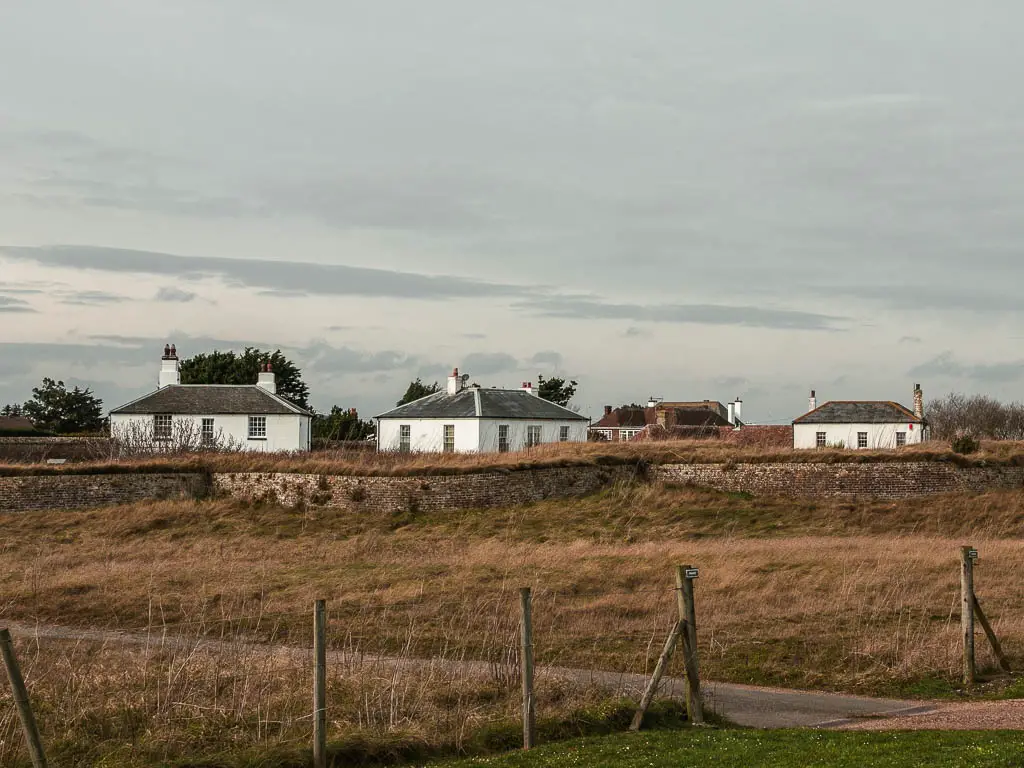 A wall in front of 3 white houses.