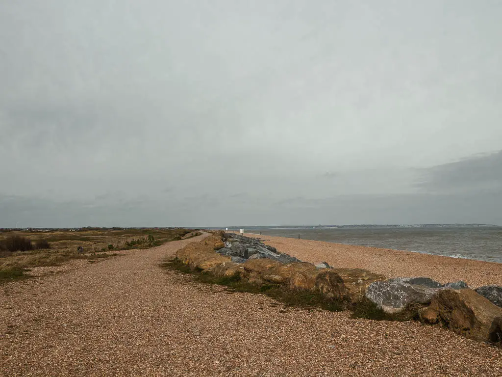 A stretch of shingle beach with a line of rocks along it on the walk from Deal to Sandwich. 