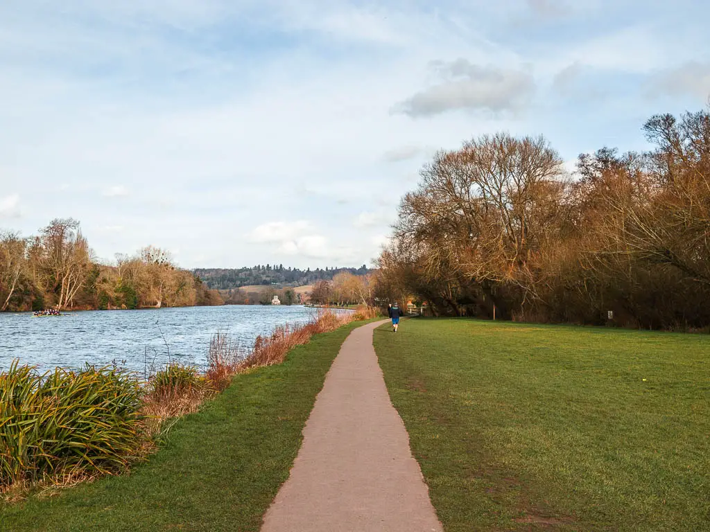 The straight Thames Path through the green on the side of the River Thames .