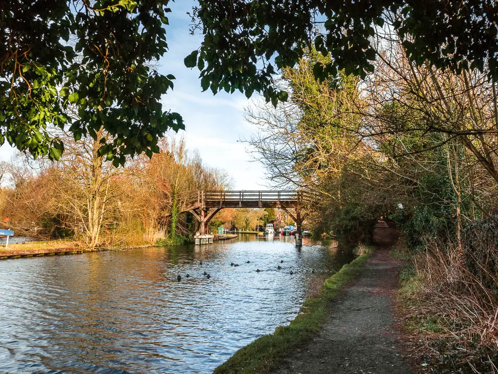 The River Thames, with a dirt path to the right leading to a wooden bridge over the river.