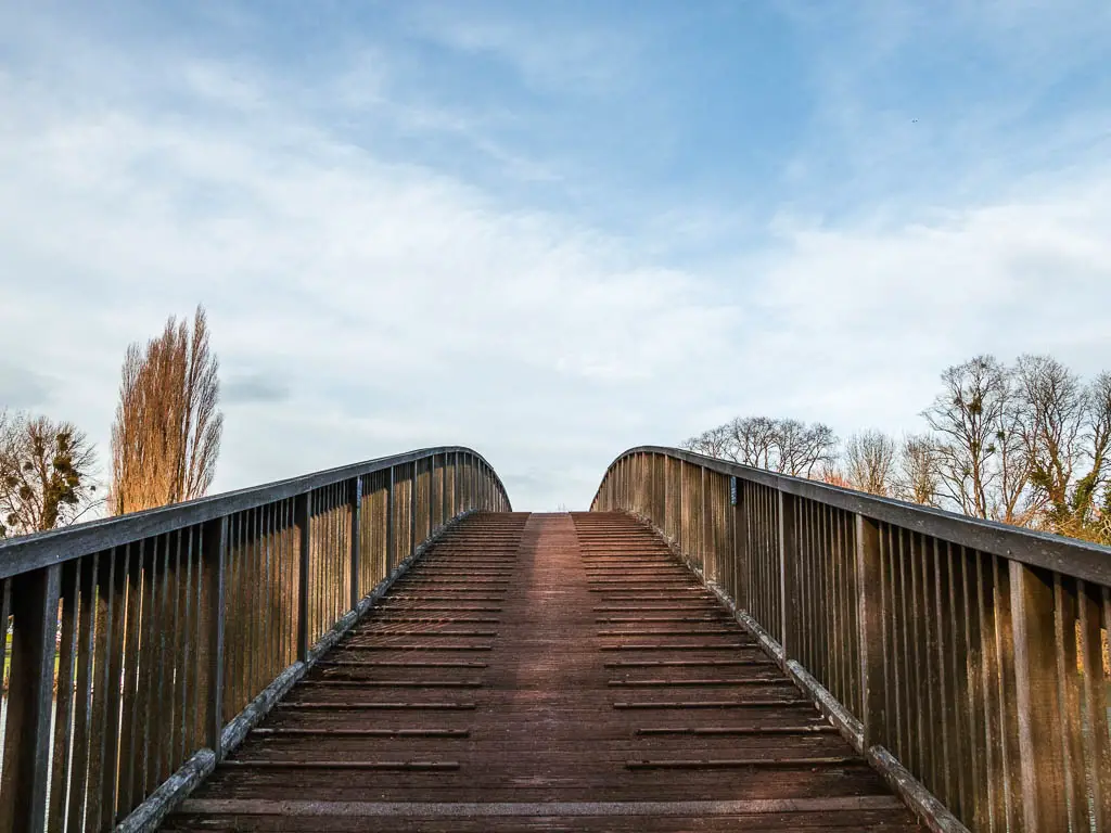 Looking up along a wooden bridge with a blue sky backdrop. 