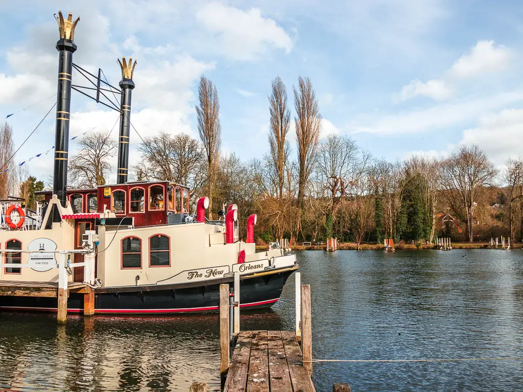 The front of a cream, black and red coloured boat in the frame on the River Thames in Marlow.