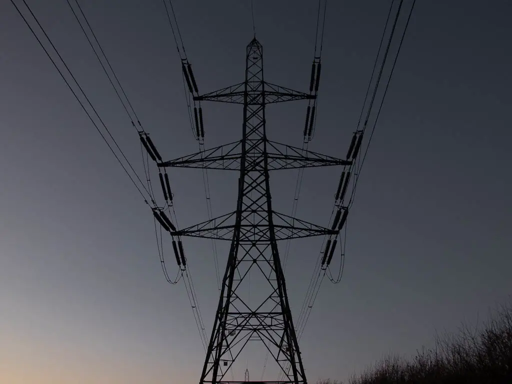 Looking up to a telephone pylon with a dark sky backdrop. 