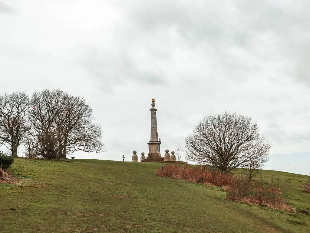 Coombe Hill monument on top of the green grass hill on the circular walk from Wendover. There are a few trees on the hill without leaves. 