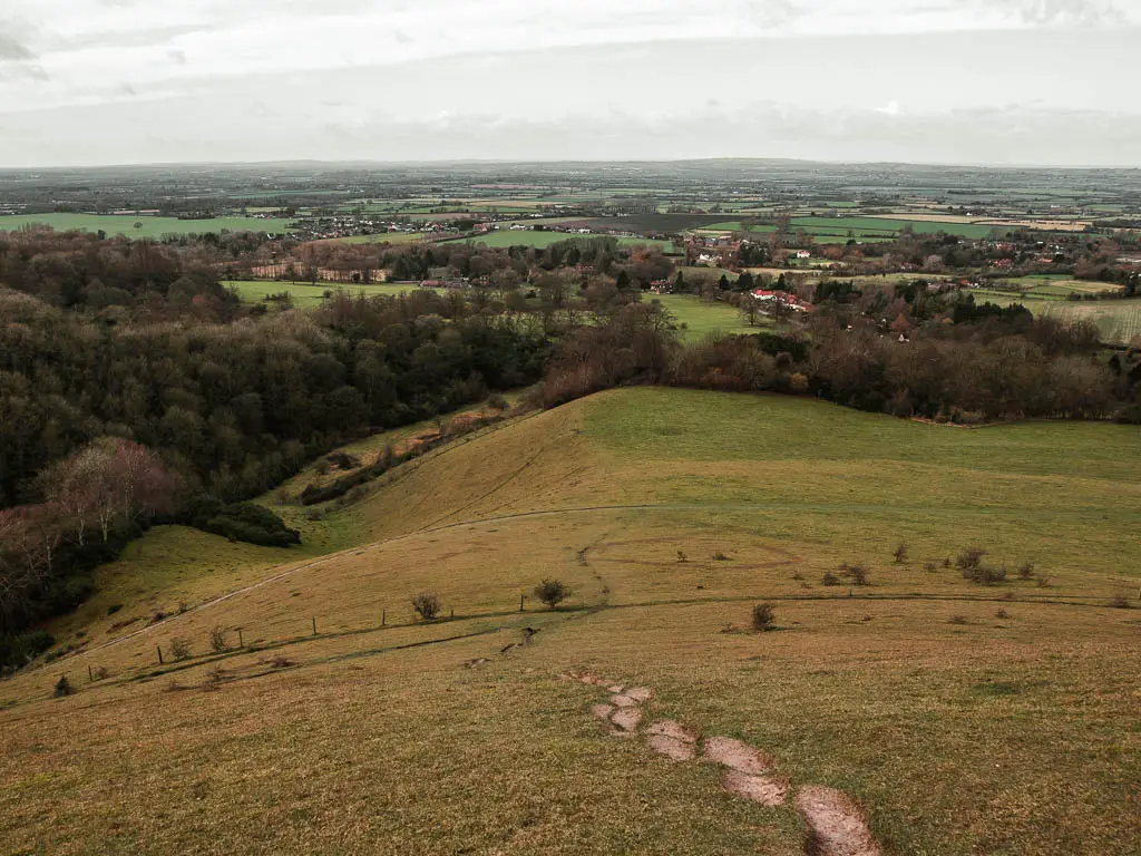 Looking down from Beacon hill to the forest and fields in the distance on the circular walk from Wendover. There are ridges in the side of the hill for stepping in.