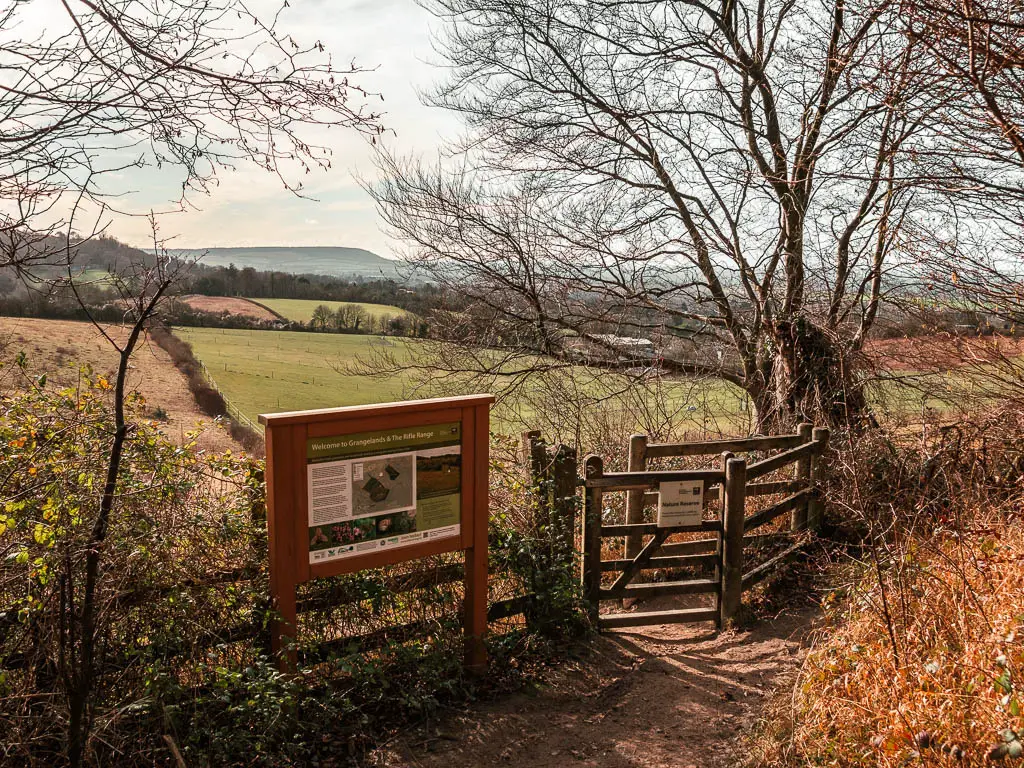 A wooden gate and information board, with a view to the rolling hills on the other side on the circular walk from Wendover and Coombe hill towards Whiteleaf Hill.