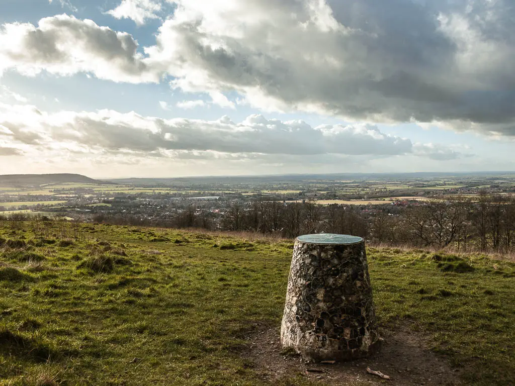 Looking past the trig point on the top of Brush Hill with a view down to Whiteleaf village and the fields in the distance. 