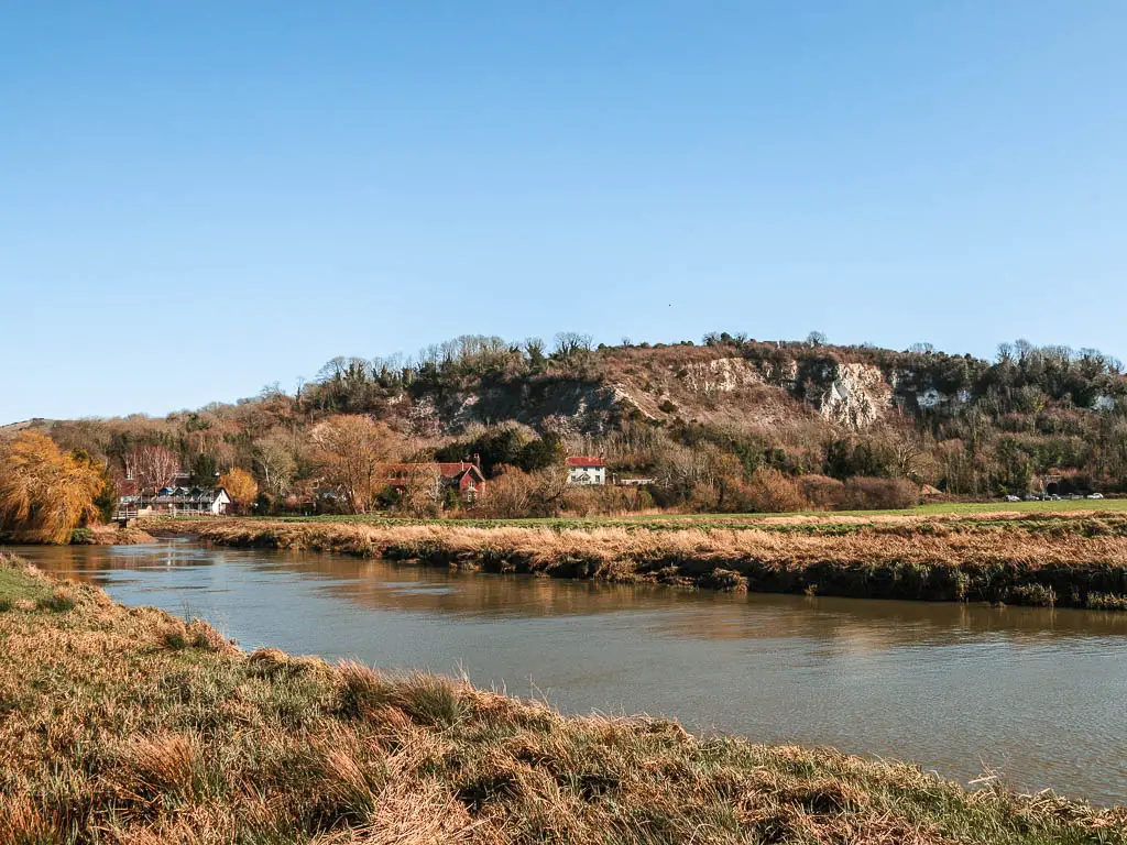 Looking across the grass and River Arun to the chalk cliff hill at the start of the walk from Amberley to Arundel.