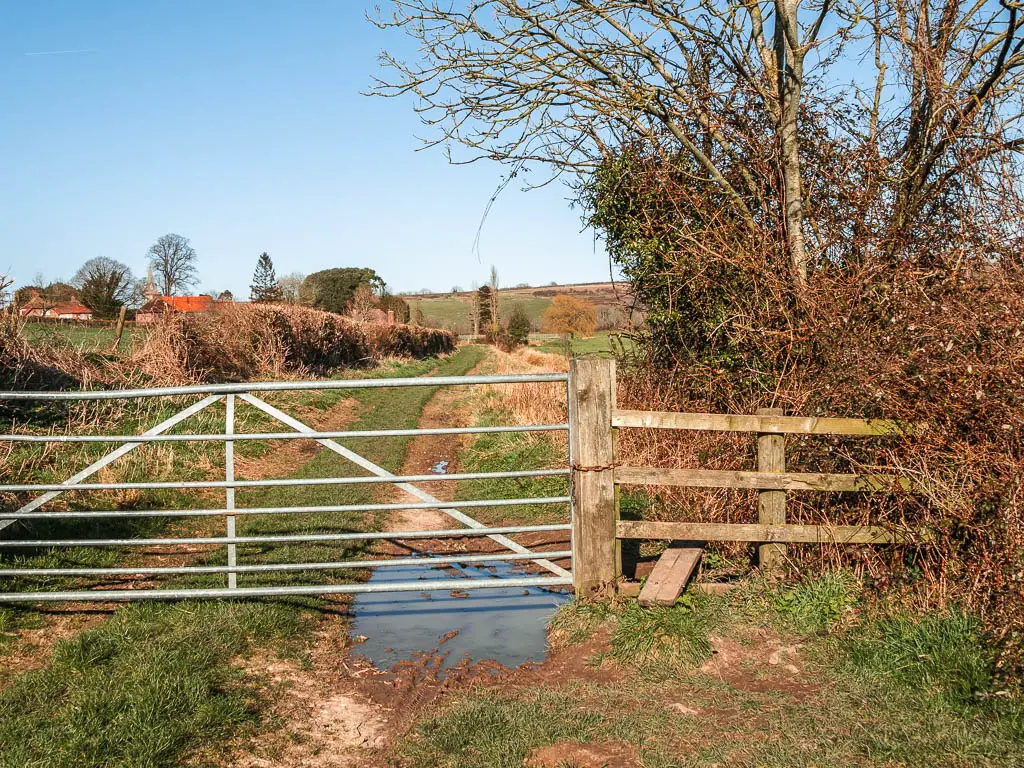 A metal gate and wooden stile across the path.