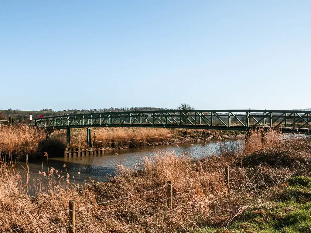 A metal bridge across the River Arun. The sky is clear blue.